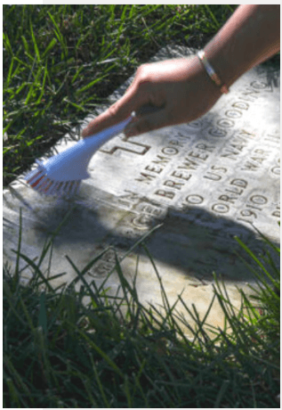 Using a brush to clean a headstone