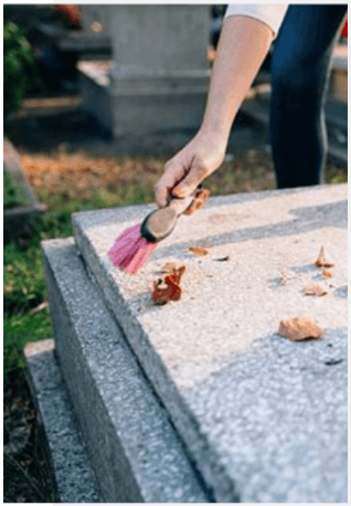 Brushing leaves from a gravestone