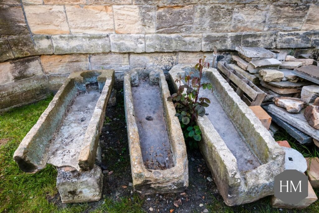 3 Stone Coffins for Tombstones outside a church. One is Broken at the foot end.
