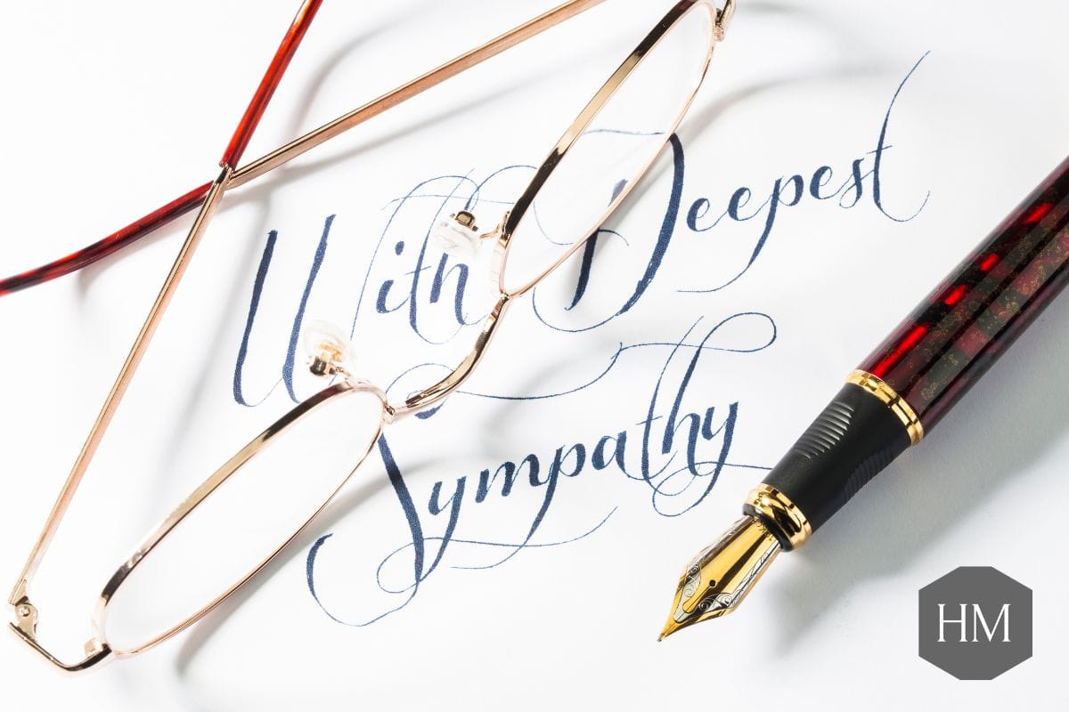 Card with "with deepest sympathy" written on with a fountain pen and glasses